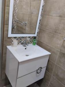 y baño con lavabo blanco y espejo. en Résidence djerba 4, en Houmt El Souk