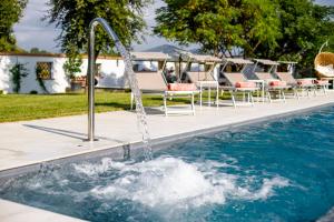 a water fountain in a pool with lounge chairs at Villa Montefalcone: Charm, Private Pool, and Chef in Orentano