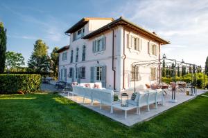 a white house with white furniture in the yard at Villa Montefalcone: Charm, Private Pool, and Chef in Orentano