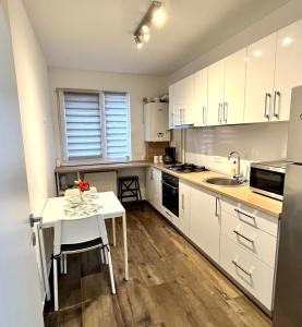 uma cozinha com armários brancos e uma mesa e cadeiras brancas em New cozy apartment in Otopeni near airport em Otopeni