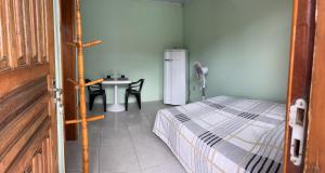 a bedroom with a bed and a table and a refrigerator at Apartamentos Pura Vida em Atlântida Sul in Xangri-lá