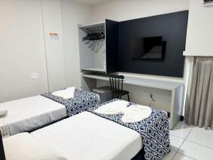 um quarto de hotel com duas camas e uma televisão de ecrã plano em Ritz Praia Hotel em Maceió