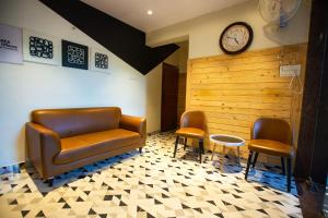 a waiting room with a couch and two chairs and a clock at Hotel Bela Goa in Panaji