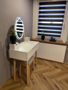 a dressing table with a mirror and potted plants on it at Apartament Rose Valley Dwa Zero in Szczytna