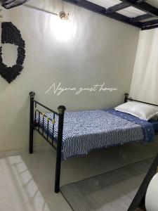 Najma guest house في Kota Bharu: سرير في غرفة مع علامة على الحائط