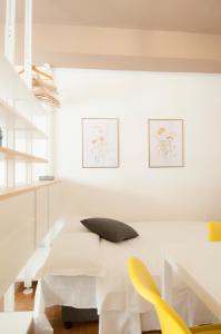 a white dining room with a white table and yellow chairs at Bologna Easy Explore - AmbrogioHost in Bologna