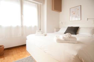een witte slaapkamer met een groot wit bed met handdoeken erop bij Bologna Easy Explore - AmbrogioHost in Bologna