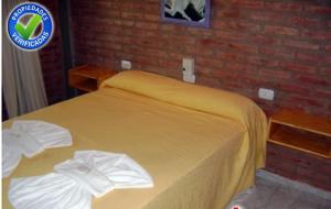 1 cama amarilla en un dormitorio con pared de ladrillo en Terrazas del Diquecito en Villa Carlos Paz