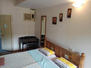 a bedroom with a bed and a table and a desk at Beach Village Holiday Homes Goa in Colva