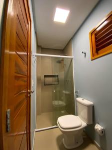 Un baño con inodoro y ducha de cristal. en Villa Palmeira Flecheiras 101, en Flecheiras 7 fotos más