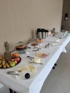 a long white table with fruits and food on it at Pousada Vida feliz in Águas de Lindoia