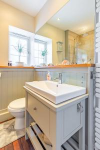 a bathroom with a white sink and a toilet at Dibley Cottage Mundesley in Mundesley +27 photos
