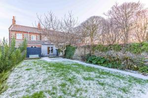 a house with a yard with snow on the ground at Dibley Cottage Mundesley in Mundesley