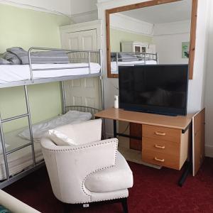 Alys apartment في لندن: غرفة مع تلفزيون وكرسي ومكتب وسرير بطابقين