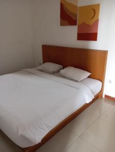 Bett mit weißer Bettwäsche und Kissen in einem Zimmer in der Unterkunft Amelle Villas & Residences Canggu in Canggu