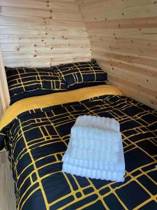 a bed with a yellow and blue comforter in a room at The Sandy Pod in Stornoway