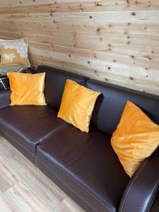 a black leather couch with yellow pillows on it at The Sandy Pod in Stornoway