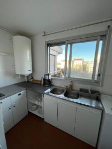 uma pequena cozinha com um lavatório e uma janela em Bel appartement à 9 minutes de Paris em Bois-Colombes