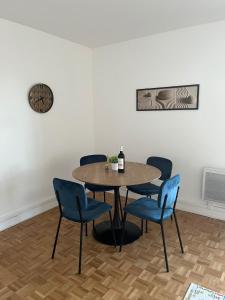 uma mesa com cadeiras azuis e uma garrafa de vinho em Bel appartement à 9 minutes de Paris em Bois-Colombes
