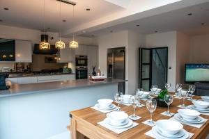 uma cozinha com uma mesa com pratos e copos de vinho em Balmoral House em Timperley