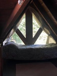 ventana en una habitación con cama en el ático en Bello Coihue en Trevelín