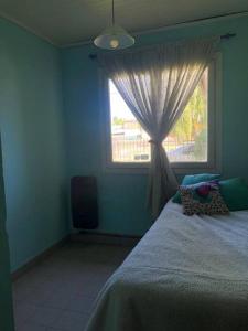 1 dormitorio con cama y ventana con cortina en Bello Coihue en Trevelín