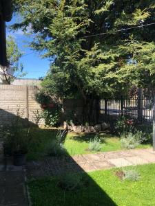 un patio con una valla y un árbol y césped en Bello Coihue en Trevelín