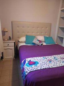 Una cama con una manta púrpura y almohadas. en Bello Coihue en Trevelín