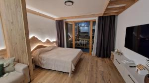 ein Schlafzimmer mit einem Bett, einem Sofa und einem TV in der Unterkunft Vuk Vučko in Jahorina
