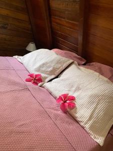 a bed with two pink flowers on top of it at Chalé no paraíso in Itacaré