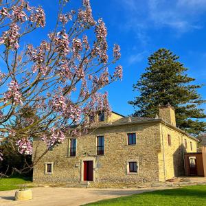 una vieja casa de piedra con un árbol en primer plano en Araucaria House en Barreiros