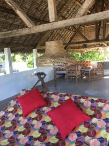 a bedroom with a bed with red pillows and a table at LE SERENITY LODGE in Mahanoro