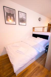 a white bed in a room with two pictures on the wall at High Standard studio. City Center. Free parking. in Warsaw