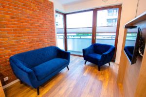 two blue chairs and a couch in a room with a brick wall at High Standard studio. City Center. Free parking. in Warsaw