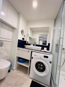 uma casa de banho com uma máquina de lavar roupa e um lavatório em Luxsor Rooms In Orbi City em Batumi