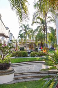 a courtyard with palm trees and a building at Hc Resort & Spa Desayuno en cortesia in Cuernavaca