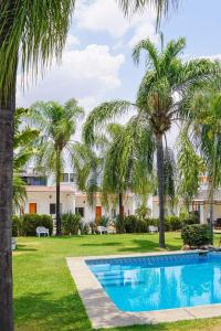 a pool in front of a resort with palm trees at Hc Resort & Spa Desayuno en cortesia in Cuernavaca