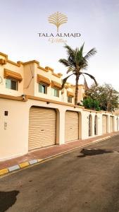 a building with two garage doors and a palm tree at Chic 3-BR Tala Almajd Villas in upscale district Alnahdah Family only in Jeddah