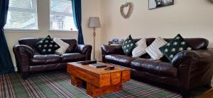 a living room with two leather couches and a coffee table at Ben Vorlich Cottage in Tarbet