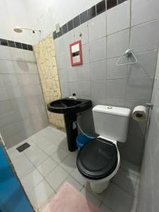a bathroom with a black toilet and a sink at Natus Hospedagem in Barra de São Miguel