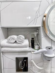 W łazience znajdują się białe ręczniki i lustro. w obiekcie Apart Wiktoria w Warszawie