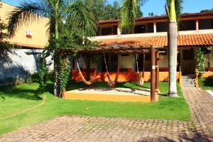 a building with a porch with palm trees in front of it at Pousada Vale da Montanha in Serra Negra