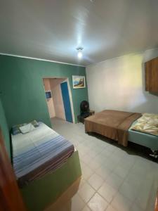 a bedroom with two beds in a room with green walls at Natus Hospedagem in Barra de São Miguel