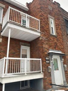 a brick house with a white balcony on it at Clara’s homestay in Montréal