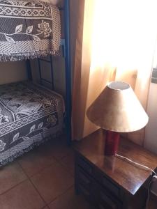 a lamp on a wooden table next to a bed at Cabañas "Las Acacias" in Villa Santa Cruz del Lago
