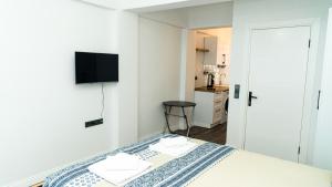 a white bedroom with a bed and a television at Port Marmaris Rooms in Marmaris