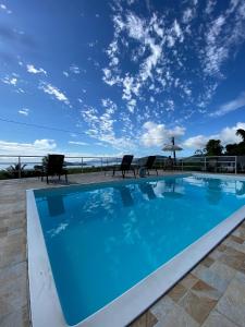 a swimming pool with chairs and a blue sky at Recanto Filadélfia in Paraty