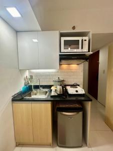 uma pequena cozinha com um lavatório e um micro-ondas em City Nest Makati with Rooftop pool and Free Netflix em Manilla