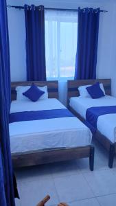 duas camas num quarto com cortinas azuis em Nyali cozy home em Mombasa