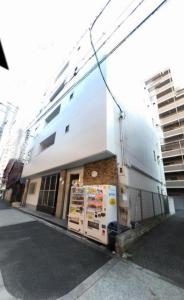 un bâtiment blanc avec un panneau sur son côté dans l'établissement Kamon INN OSAKA, à Osaka